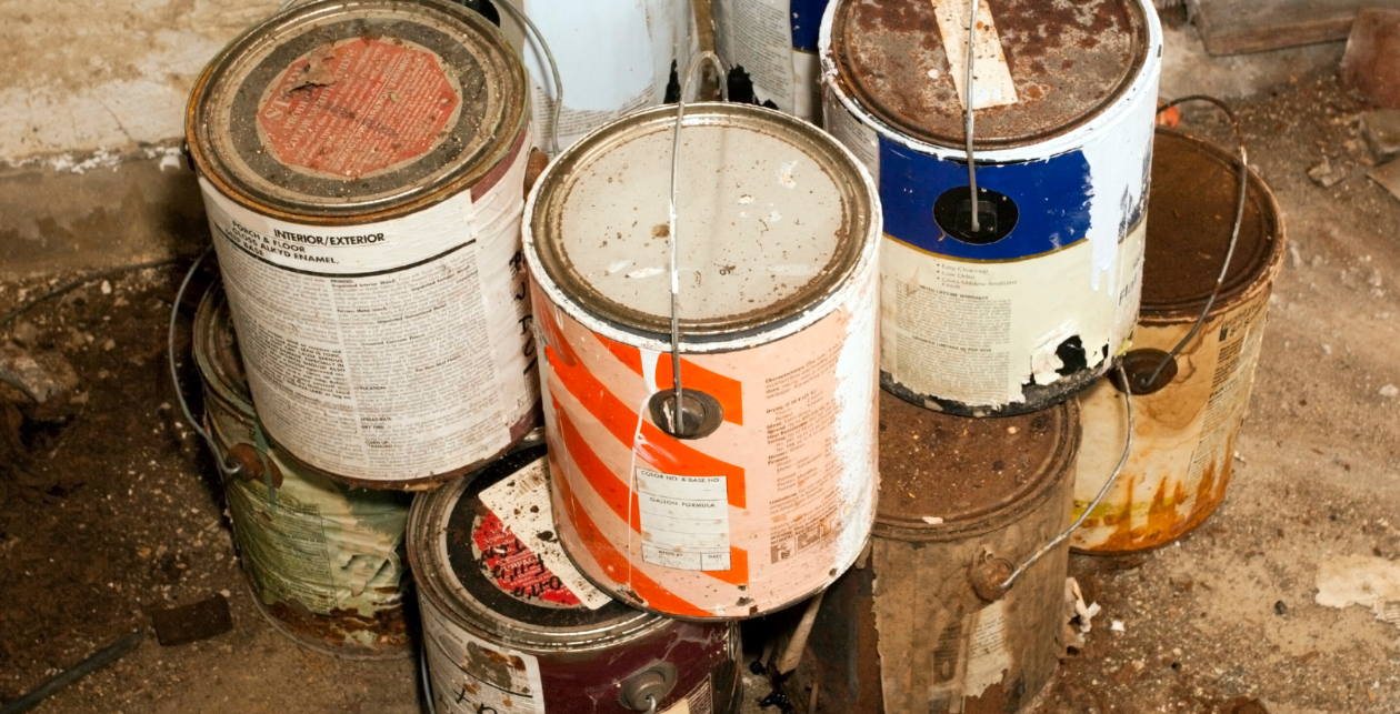 Stack Of Old Rusted Paint Cans In Mixed Colors On A Concrete Floor Against A Wall
